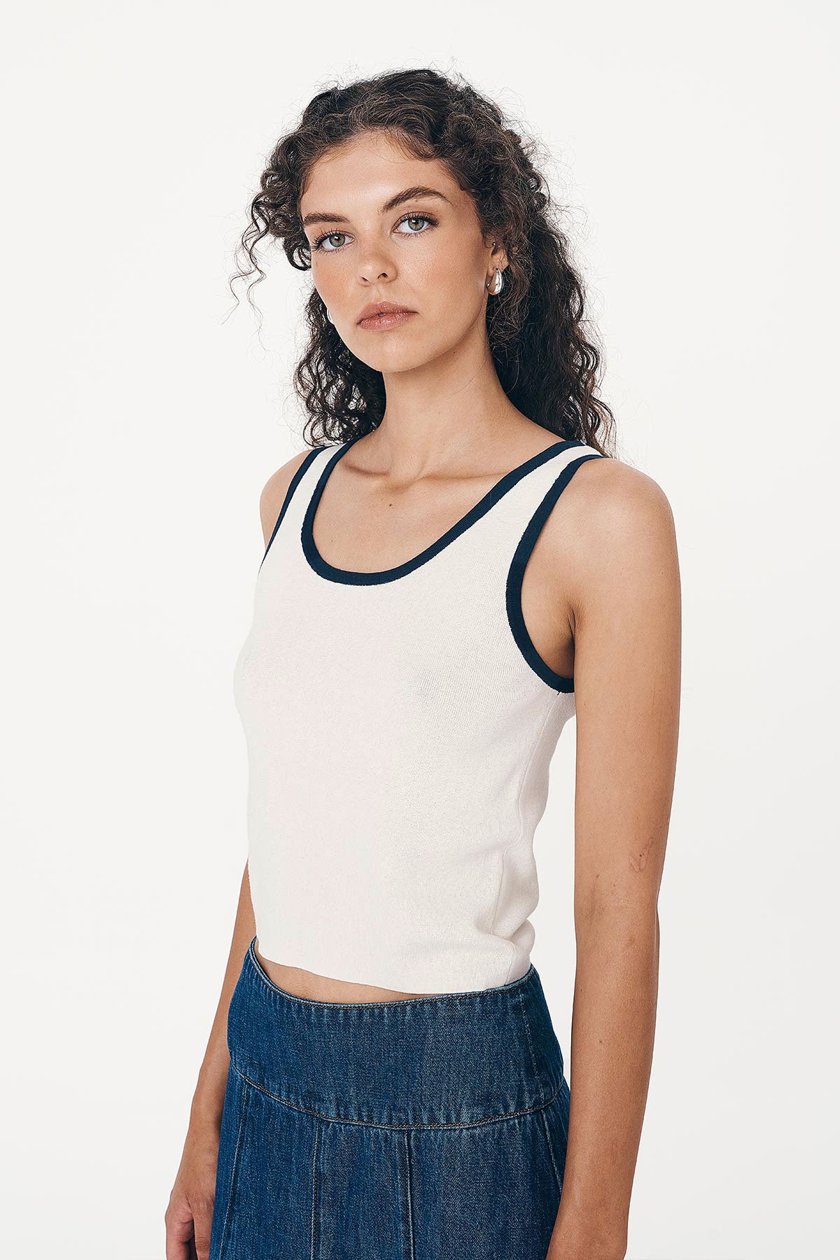 Angled studio view of model wearing a Blake Contrast Knit Tank top in cream with Ink blue trim, styled with the Vashti Denim Midi Skirt by ROWIE the Label.