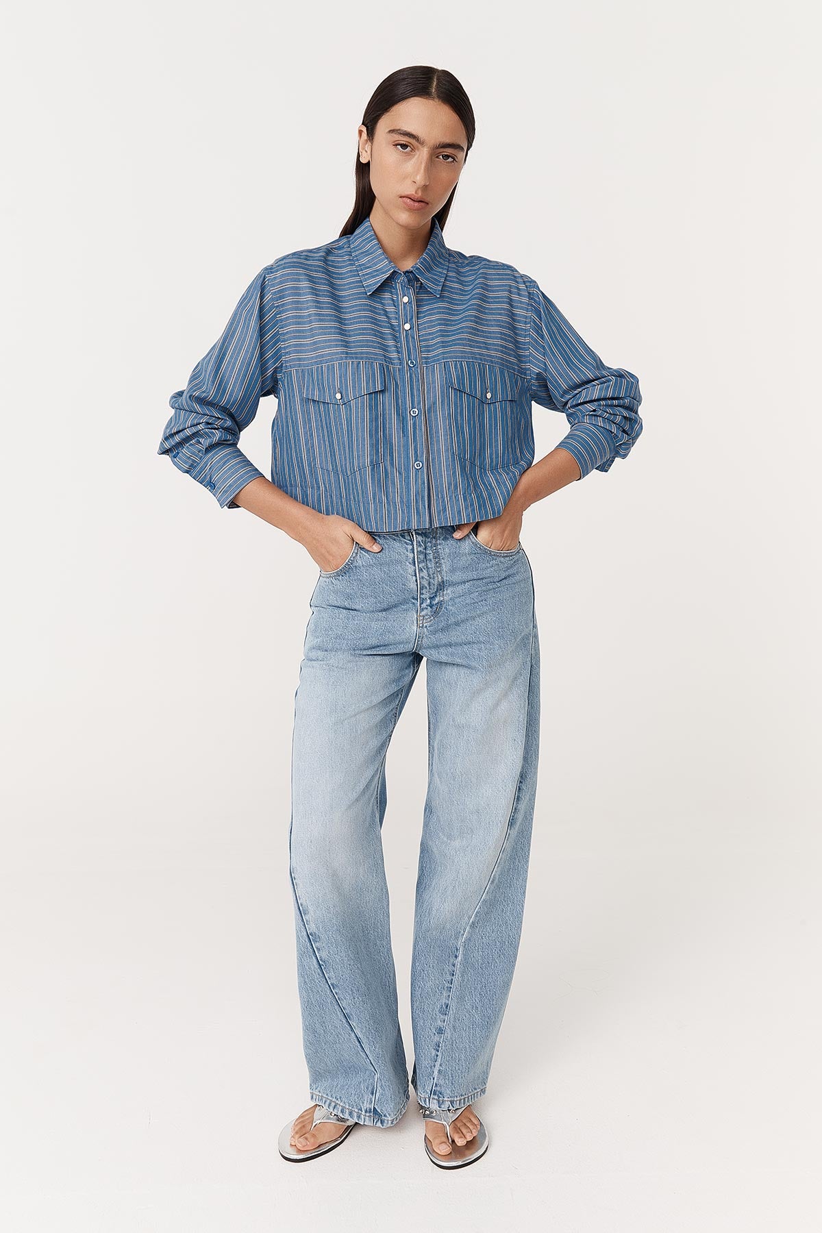 Model wearing a Cole Stripe Crop Shirt in Lagoon, paired with the Percy Curve Seam Jeans in Faded Blue by ROWIE the Label, front studio view.