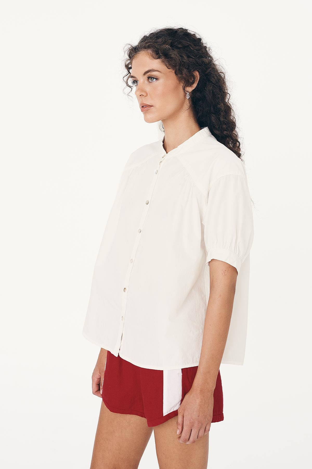 Side detail of the Cora Spring Blouse buttoned-up with 3/4 length sleeves and Red Linen Shorts