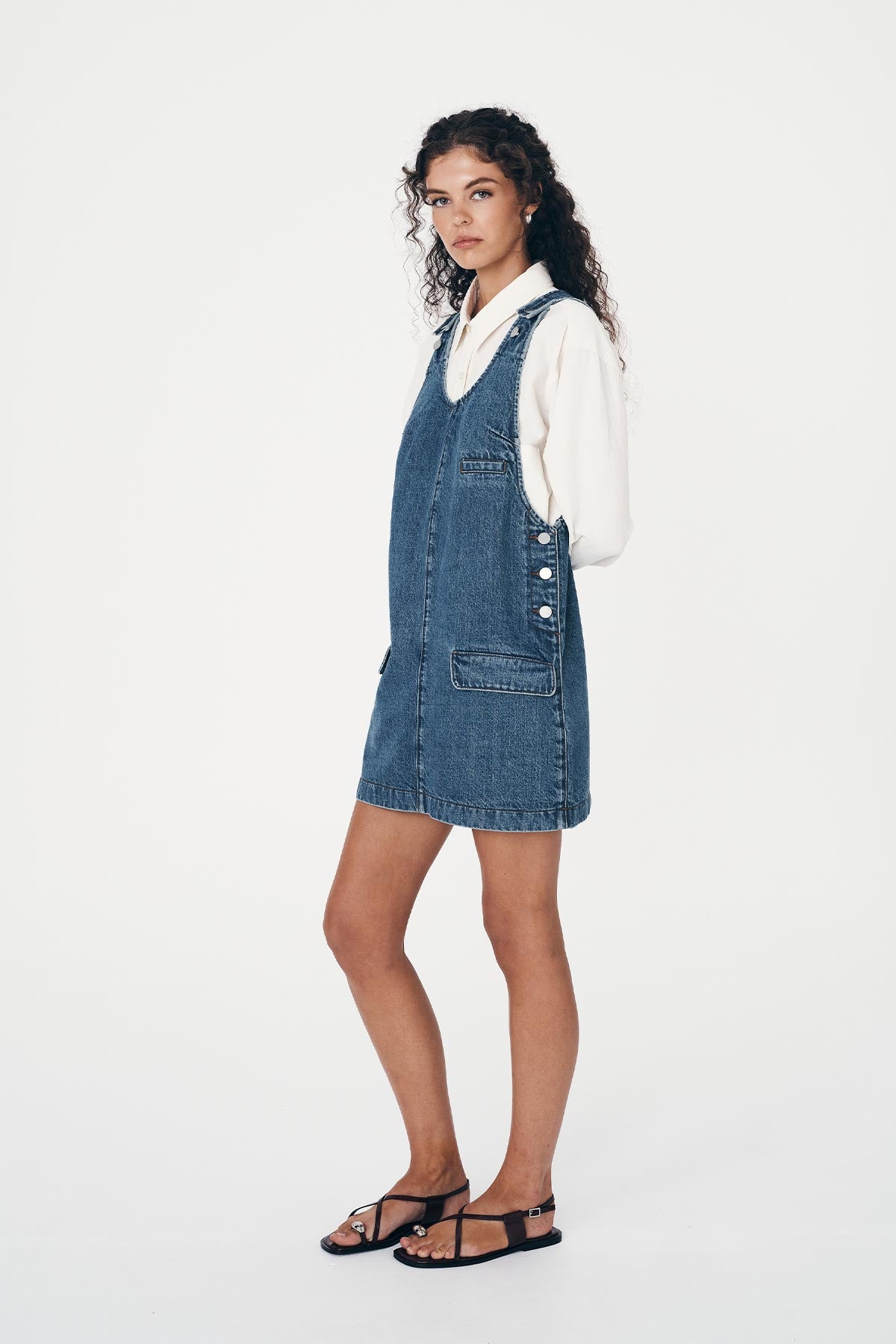 Side view of the Franka Denim Mini Dress highlighting the side buttons and welt pockets. worn over the top of the Ramona Silk Shirt in White