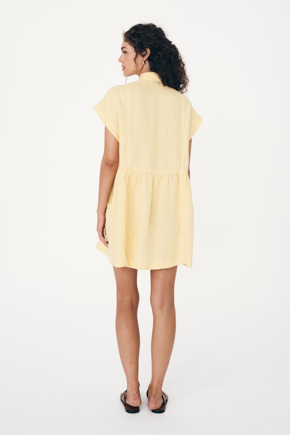 Woman wearing a yellow, french linen dress on a white background