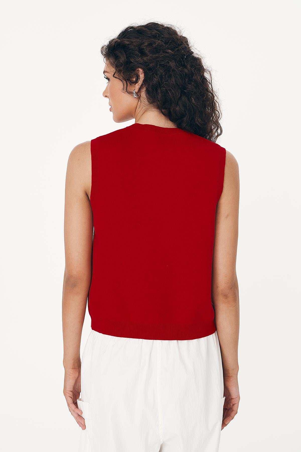 Model wears red Cotton Knit Vest, paired with white Cargo Pants, showing detail from behind