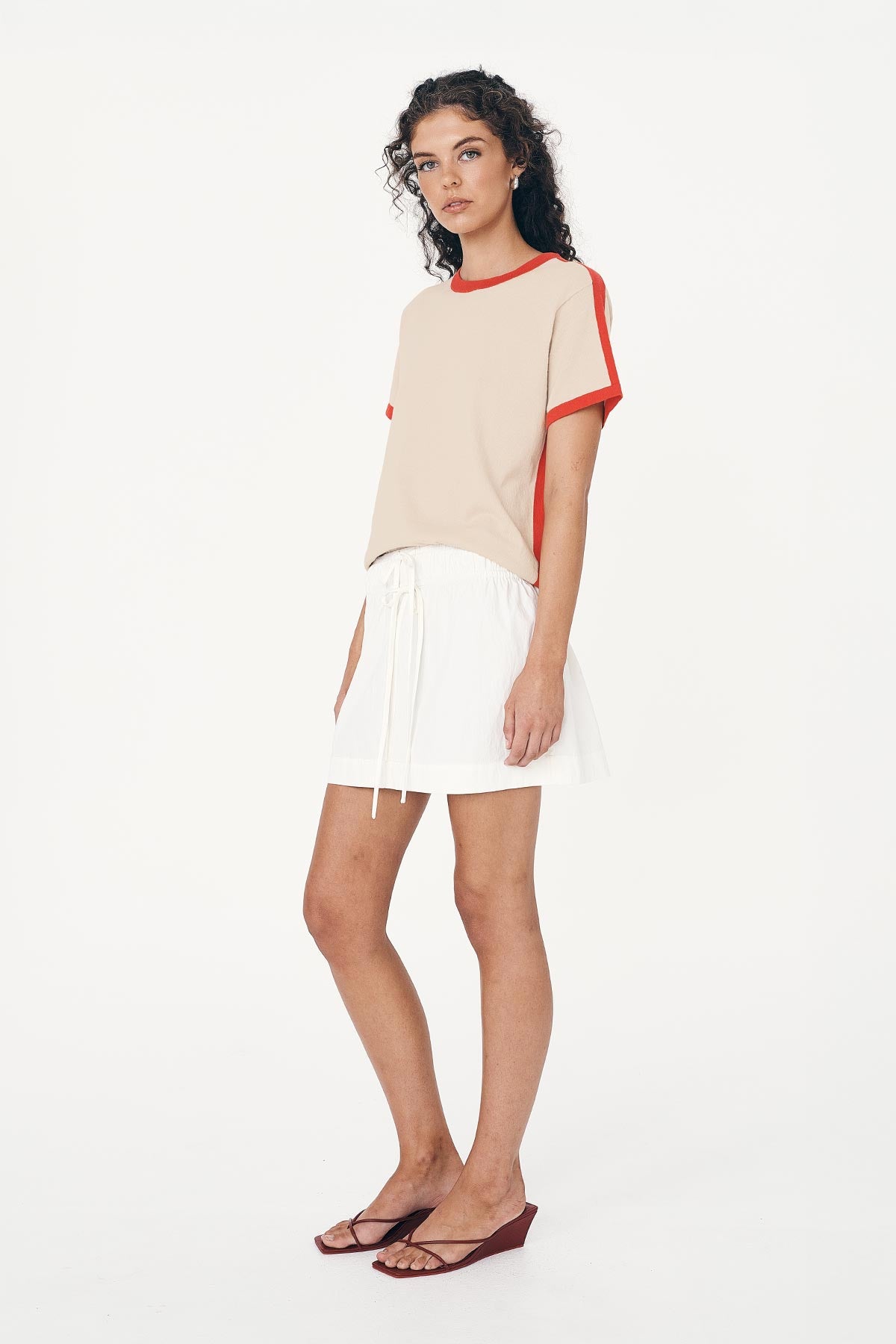 Model wears ROWIE The Label Jessica Cargo Mini Skirt in White with an elasticised waist and double tie front. Paired with the Rania Contrast Knit Tee, a Cotton-Knit Tee-shirt with a relaxed fit.