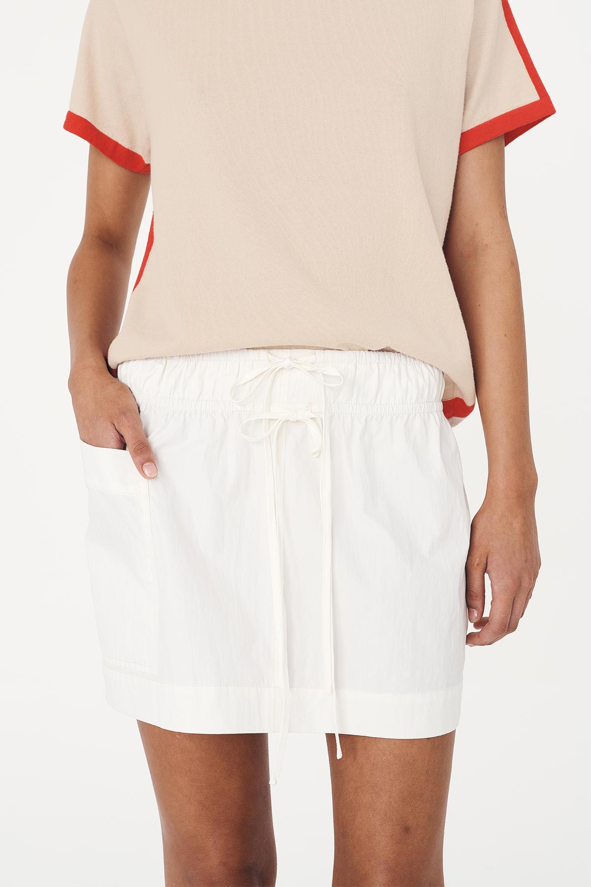 Jessica Cargo Mini Skirt in White with double, centre-front ties. Paired with the Rania Contrast Knit Tee, defined by its contrast red trims and relaxed fit.