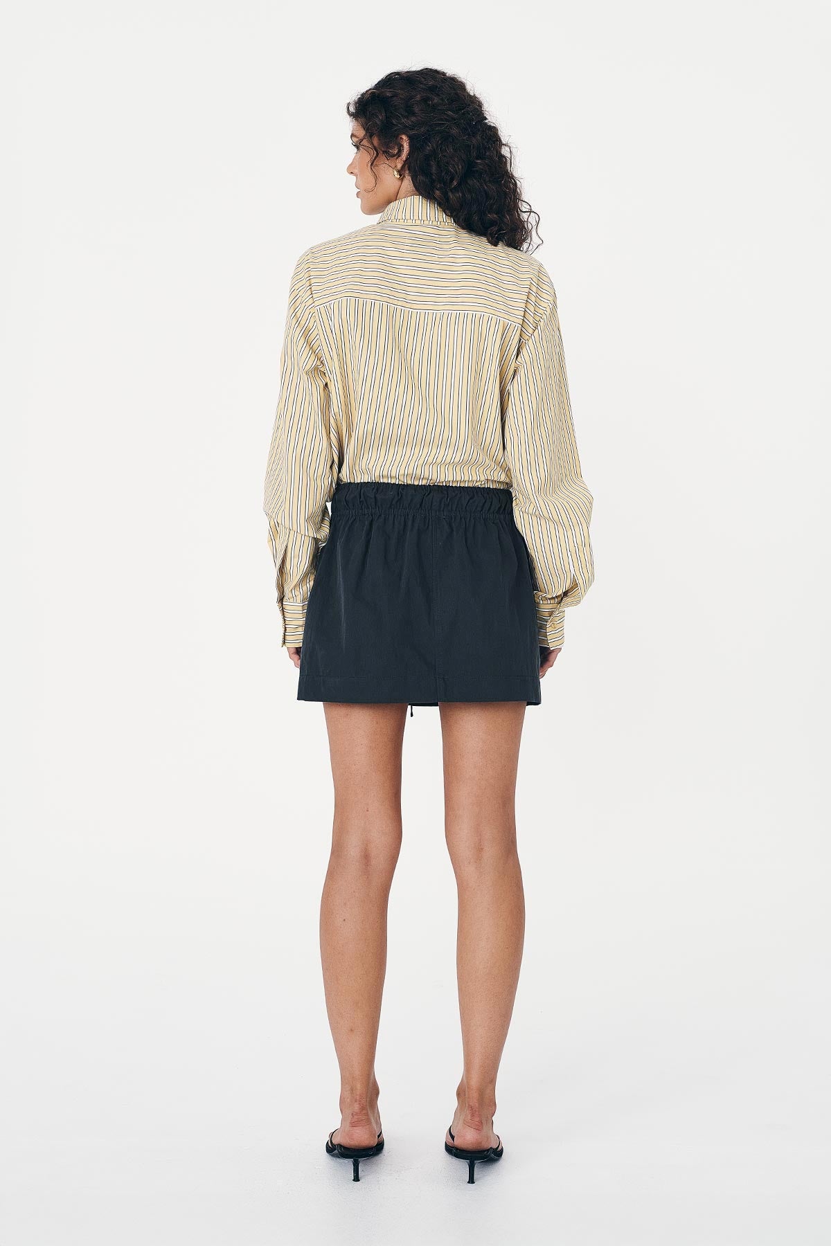 Model wears Black Cargo Mini Skirt, paired with a cropped, stripe shirt 
