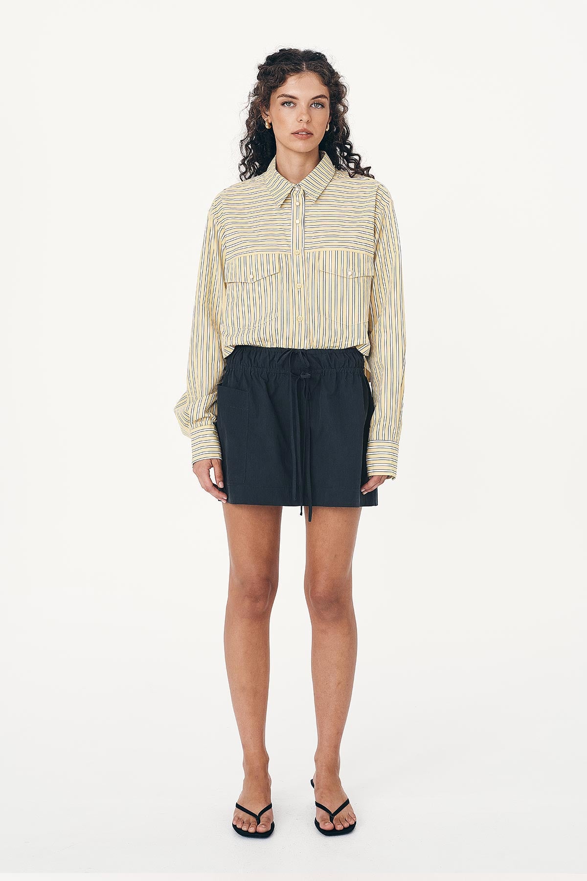 Model wears Jessica Cargo Mini Skirt in Black, paired with the Cole Stripe Crop Shirt in sunflower yellow