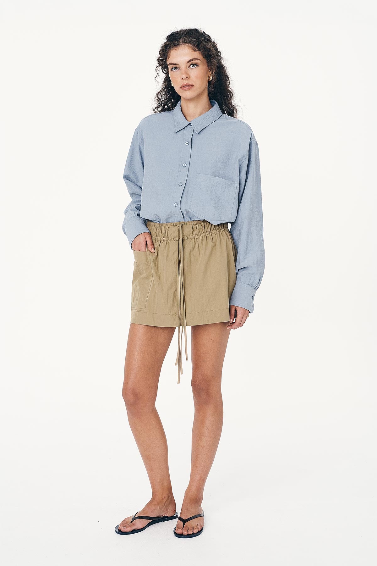Model wearing a Jessica Cargo Mini Skirt in Washed Khaki, paired with the Ramona Silk Long Sleeve Shirt in Periwinkle Blue by ROWIE the Label, front studio view.