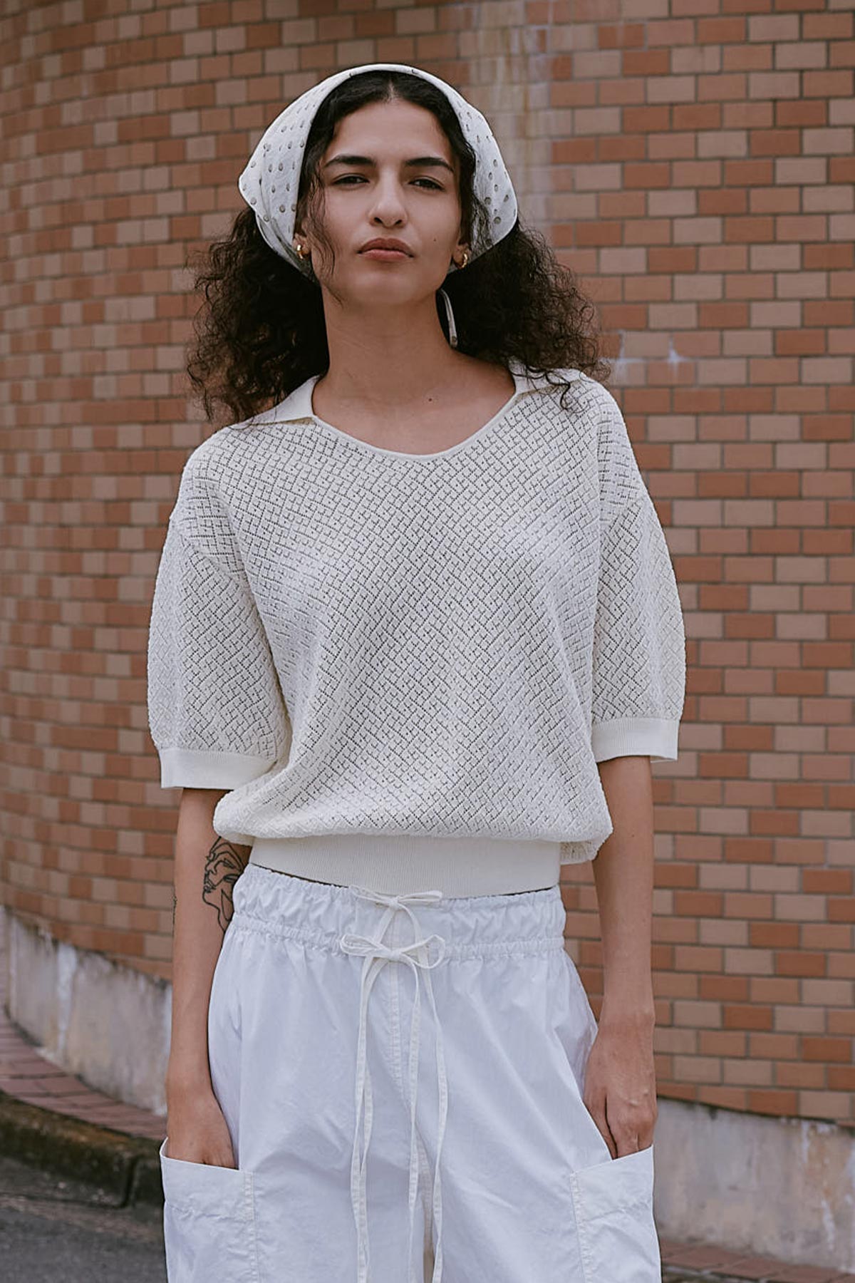 Model wears ROWIE The Label Lorretta Pointelle Knit Top, paired with a Frannie Silk Scarf styled as a head scarf and Jessica Cargo Pants in White