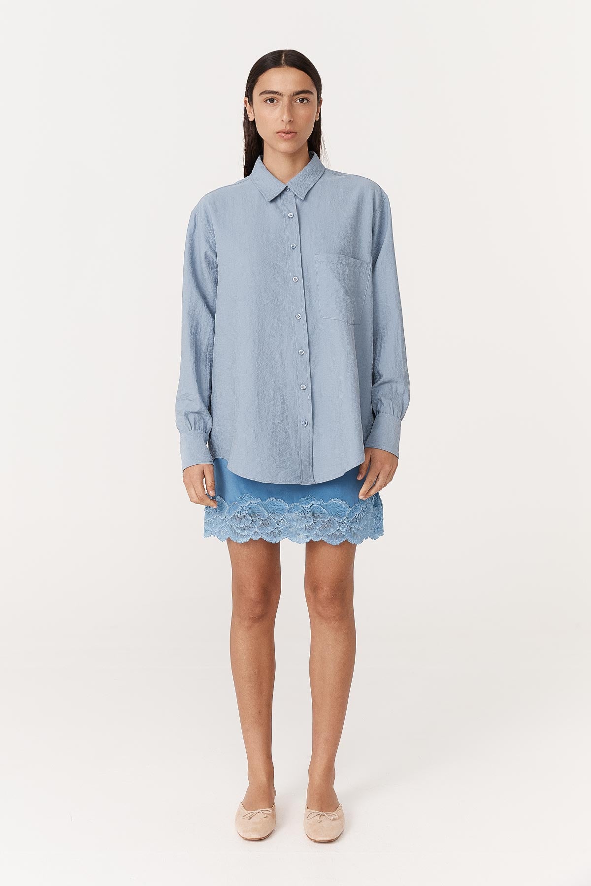 Model wearing a Marina Silk Mini Skirt in Cornflower, paired with the Ramona Silk Long Sleeve Shirt in Periwinkle by ROWIE the Label, front studio view.