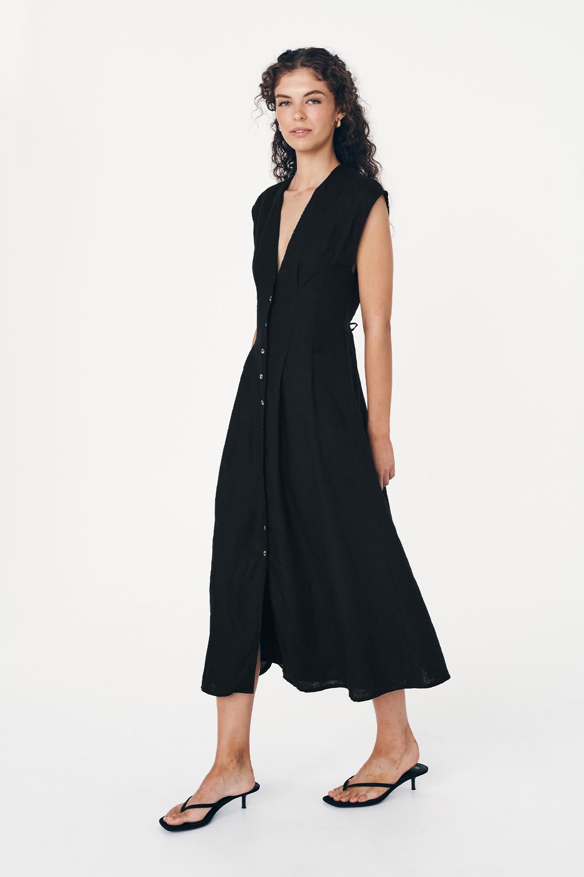 Side shot of the Mira Linen Midi Dress in Black. Showing a button-through front, and tie-back waist by ROWIE The Label