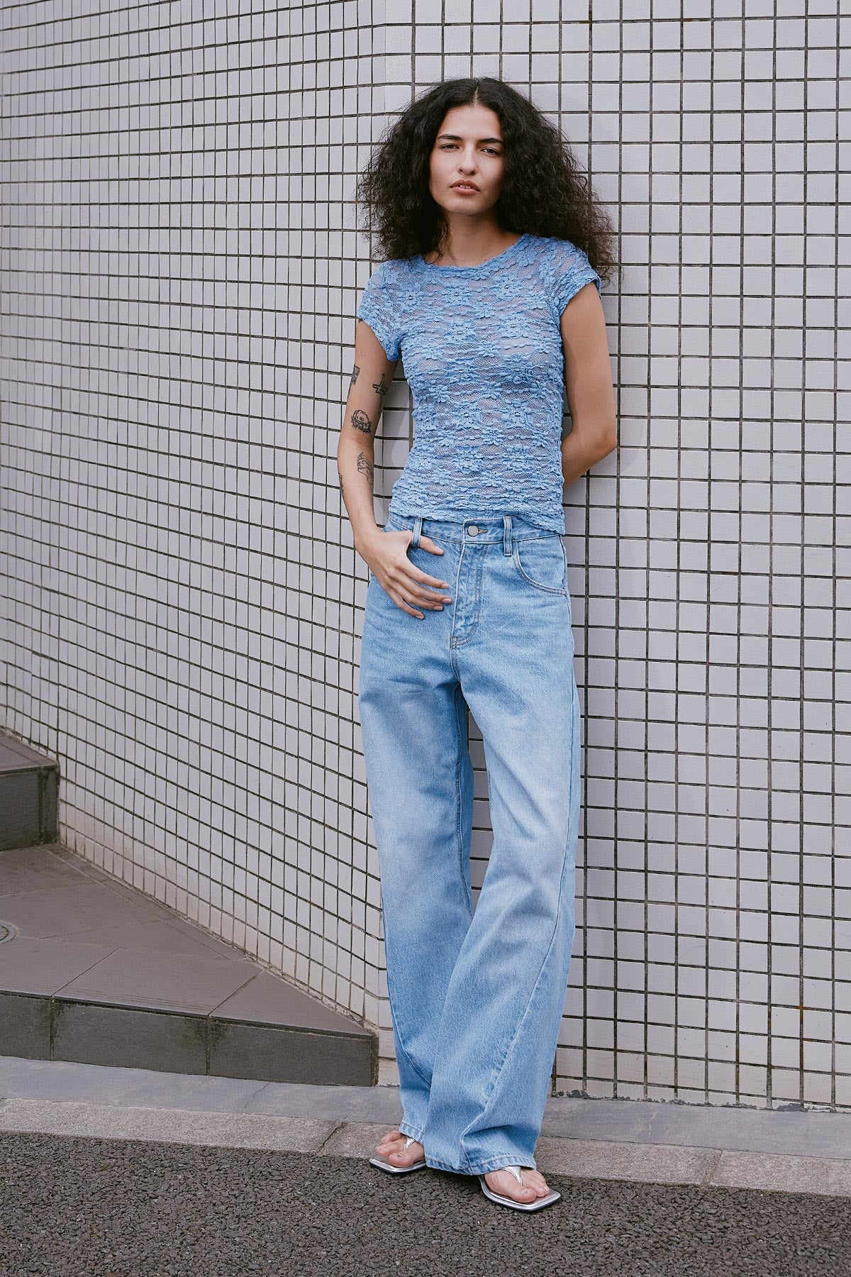 Model wearing Percy Curve Seam Jeans in Faded Blue, styled with the Galo Sunflower Lace Tee in Periwinkle by ROWIE the Label, lifestyle shot on a Tokyo street.