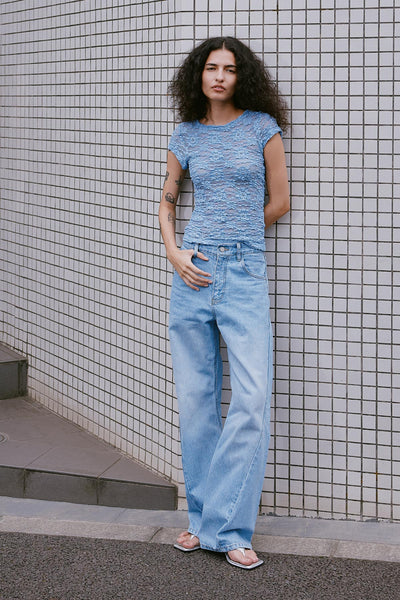 Model wearing Percy Curve Seam Jeans in Faded Blue, styled with the Galo Sunflower Lace Tee in Periwinkle by ROWIE the Label, lifestyle shot on a Tokyo street.