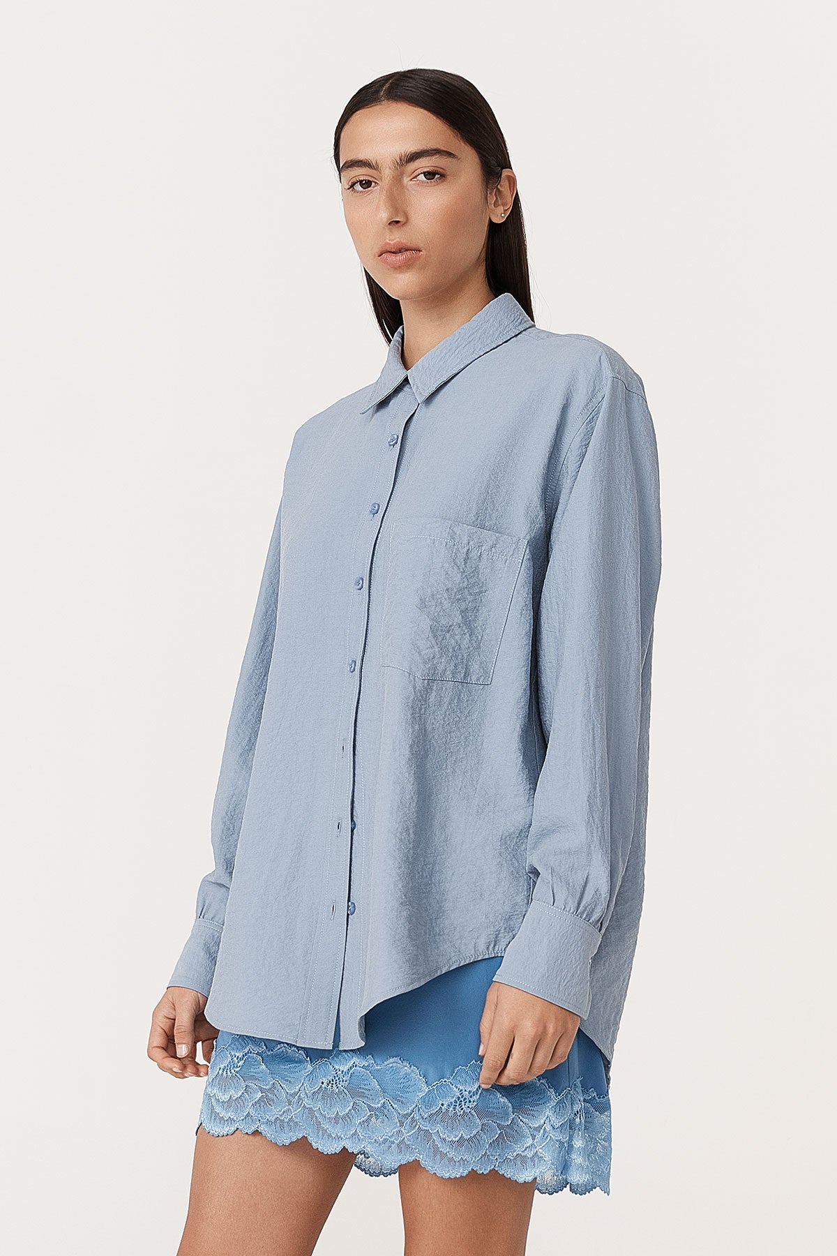 Angled studio view of model wearing a Ramona Silk Long Sleeve Shirt in Periwinkle, styled with the Marina Silk Mini Skirt in Cornflower by ROWIE the Label.