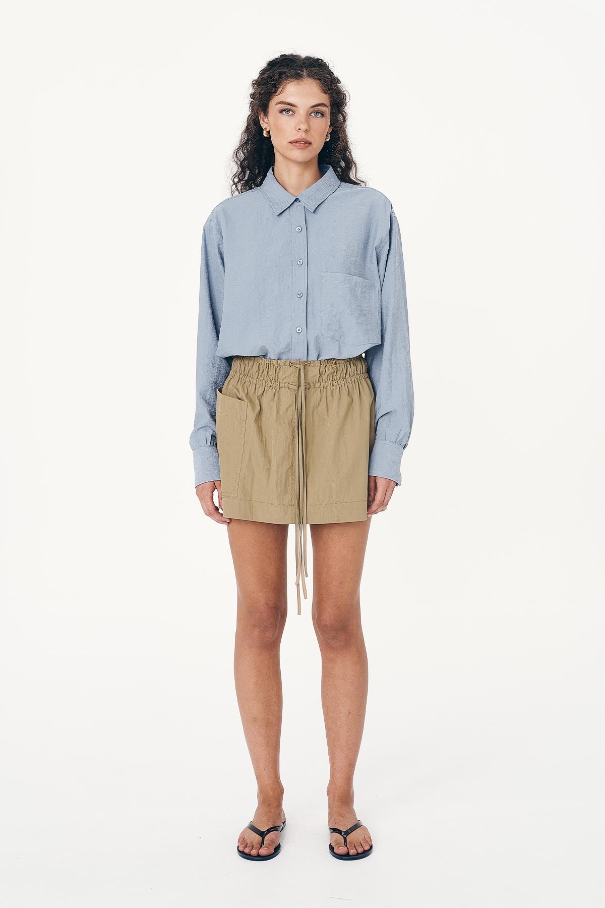 Full-body studio view of model wearing a Ramona Silk Long Sleeve Shirt in Periwinkle, styled with the Jessica Cargo Mini Skirt in Washed Khaki by ROWIE the Label.