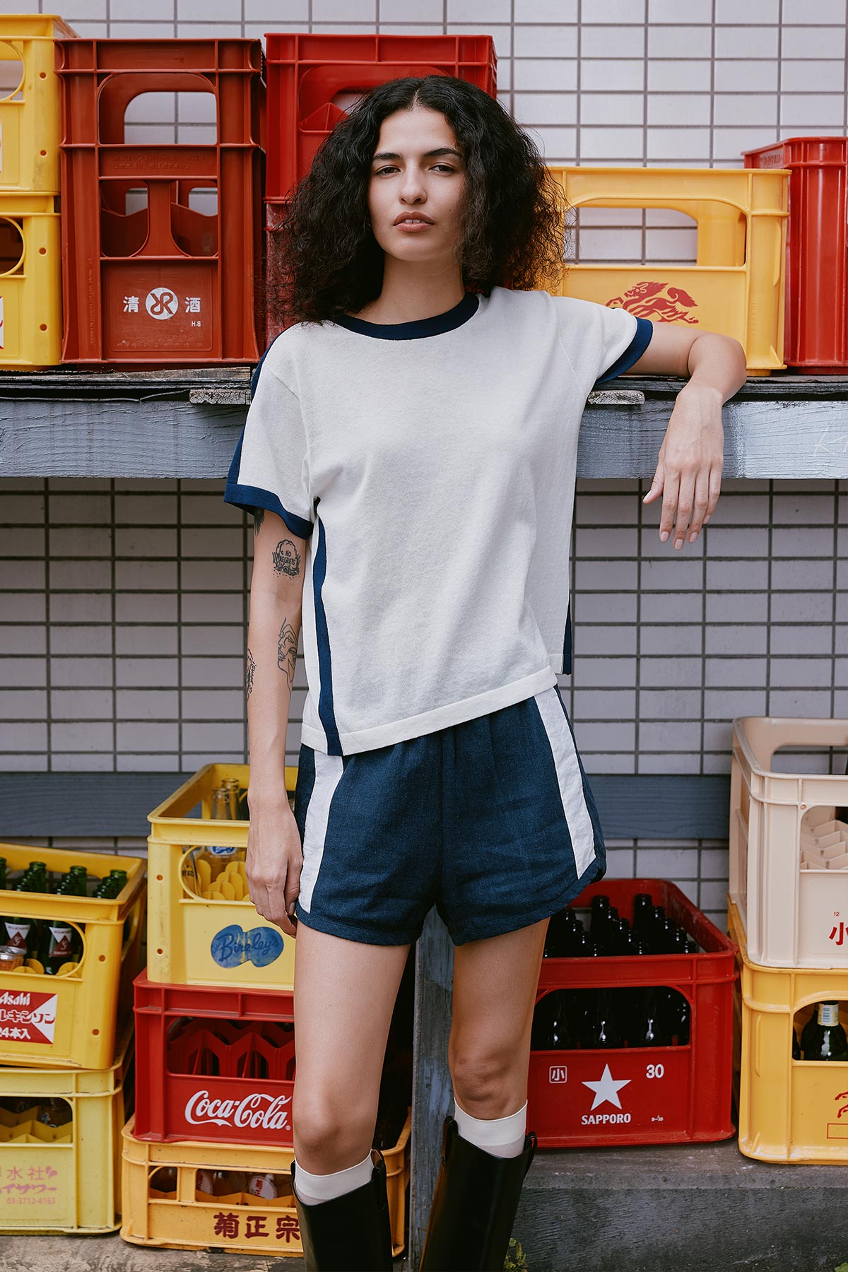 Model wearing a Rania Contrast Knit Tee in Ink, styled with the Simone Linen Shorts in Ink by ROWIE the Label, lifestyle shot on a Tokyo street.