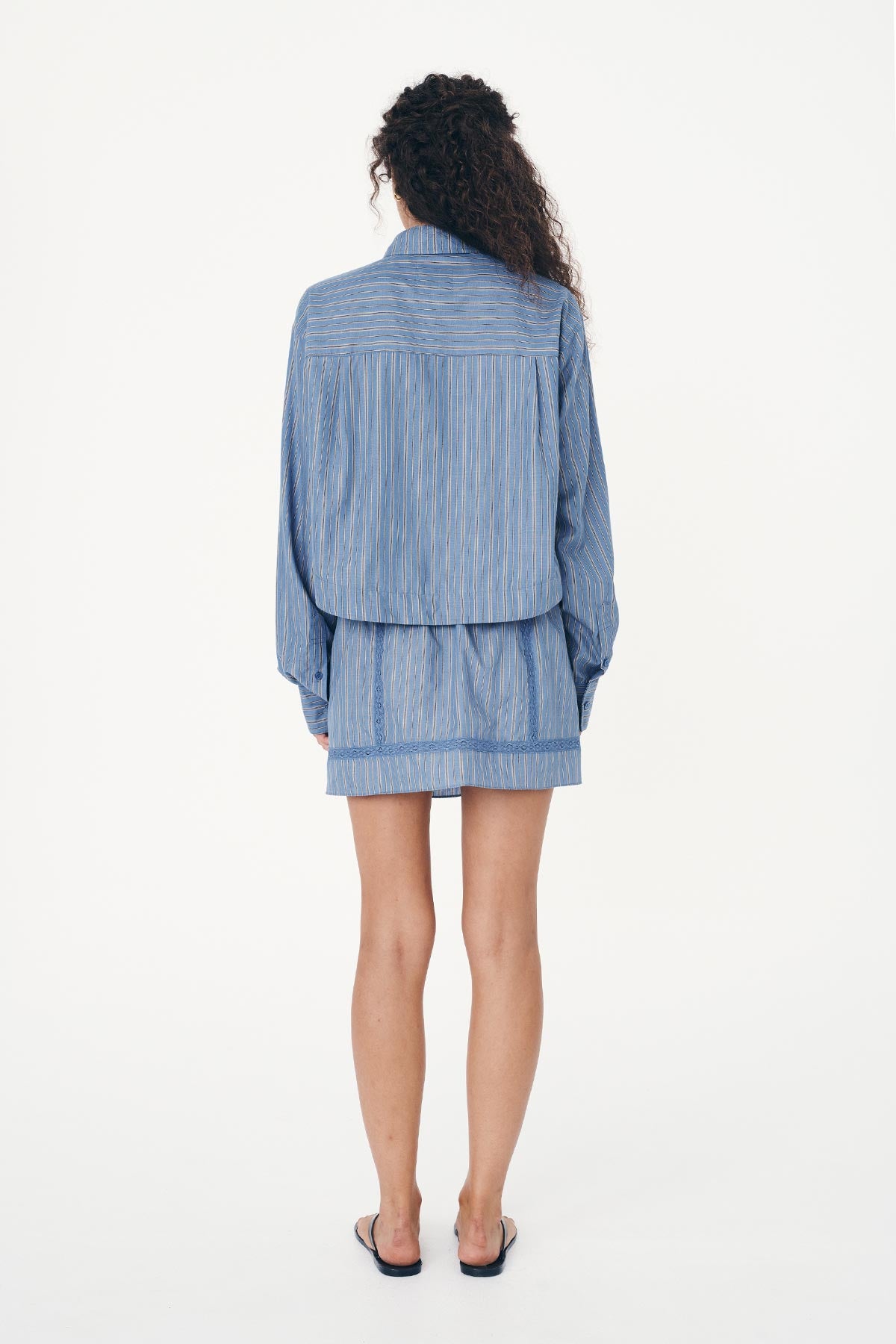 Back studio view of model wearing a Suri Lace Mini Skirt in Lagoon, styled with the Cole Stripe Crop Shirt in Lagoon by ROWIE the Label.