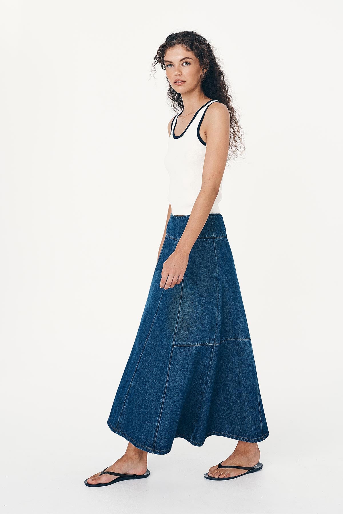 Angled side studio view of model wearing a Vashti Denim Midi Skirt in Classic Denim, styled with the Blake Contrast Knit Tank in Cream with Ink trim by ROWIE the Label.